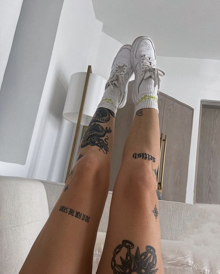 two people with tattoos on their legs sitting on a bed