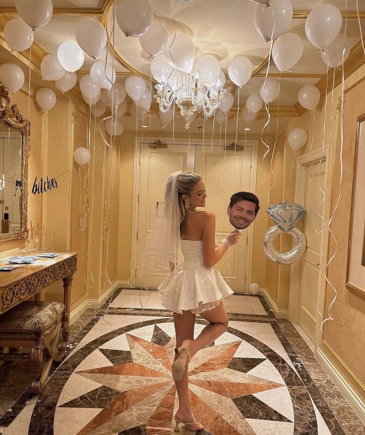 a man and woman are standing in a hallway with balloons hanging from the ceiling above them