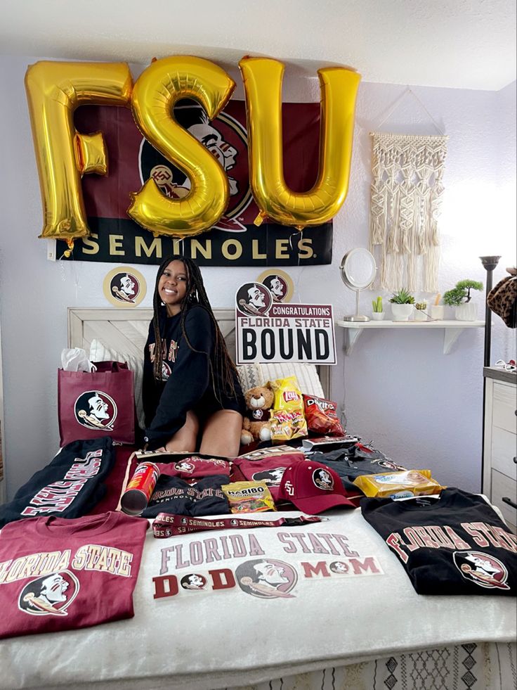 a woman sitting on top of a bed in front of a sign that says fsu