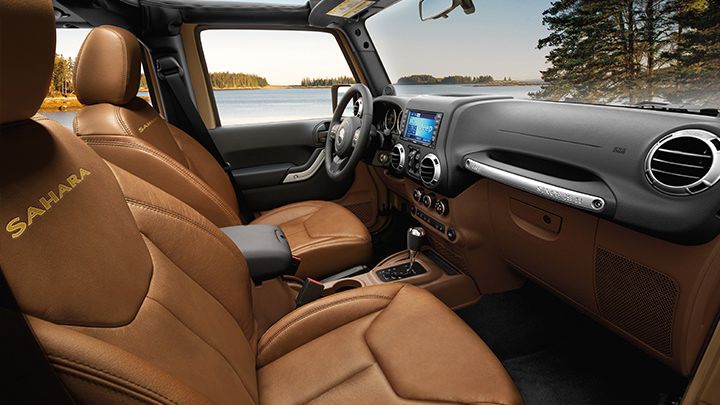 the interior of a vehicle with brown leather seats and dashboards, along with an ocean view