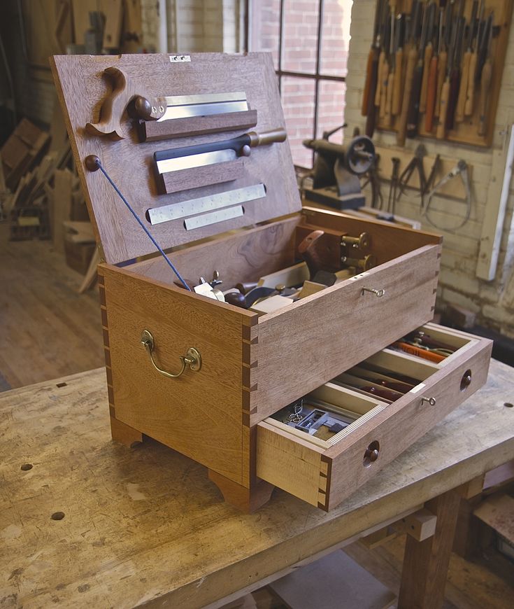 an open wooden tool box sitting on top of a table