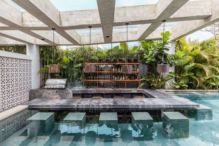 an outdoor living area with a pool and lounge chairs in the center, surrounded by greenery