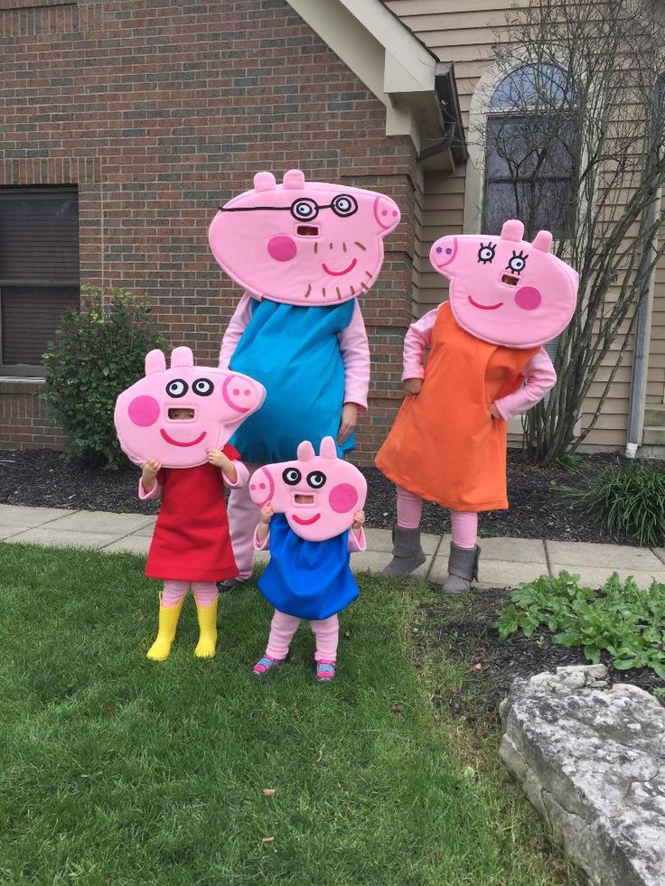 peppa pig family costumed in front of a house with two kids and one adult