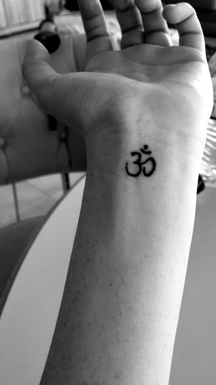 a person with a tattoo on their wrist that has an om symbol tattooed on it