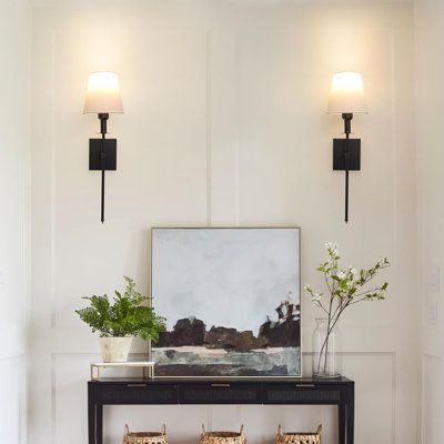 a living room with two lamps on the wall and a bench in front of it