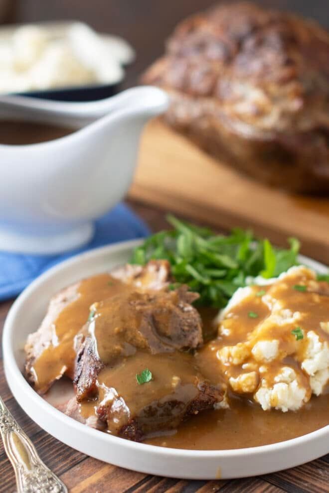 a white plate topped with meat and gravy covered in gravy on top of a wooden table