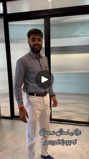 a man standing in front of a window wearing white pants and a checkered shirt