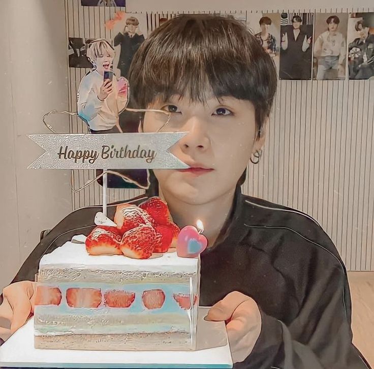 a person holding a cake with strawberries on it and a sign that says happy birthday