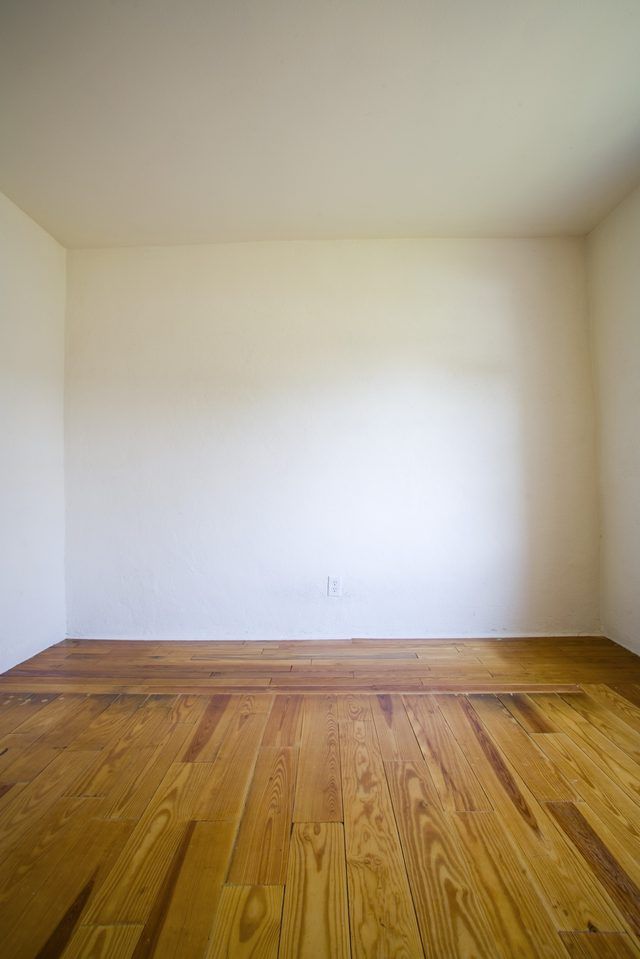 an empty room with hard wood floors and white walls