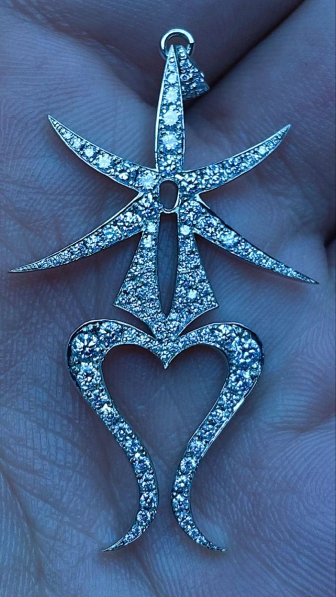 a person is holding a diamond pendant in their hand with the shape of a heart