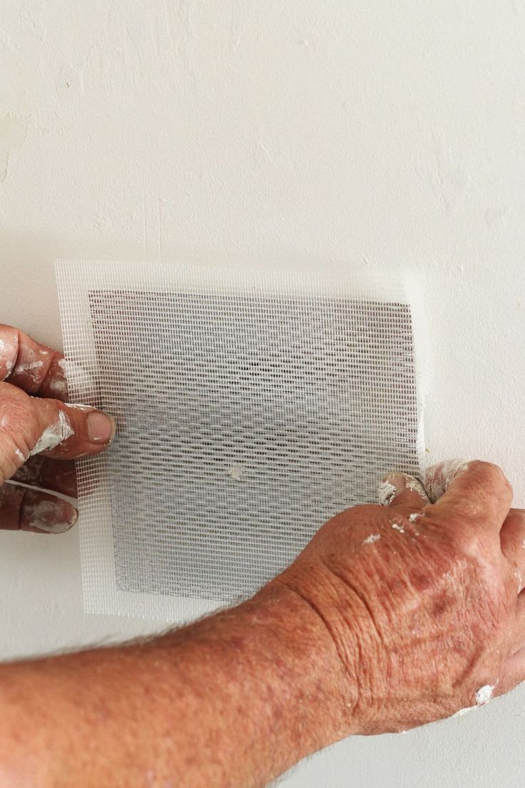 an older person is painting the wall with white paint