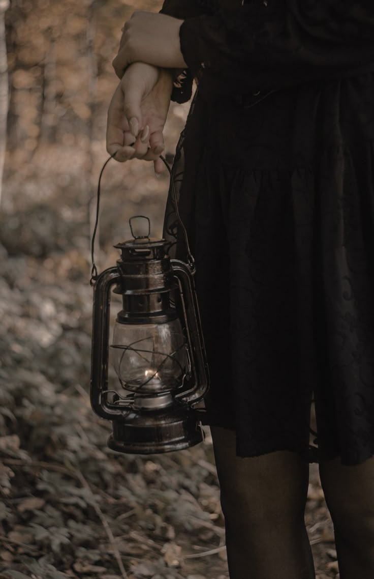 a woman holding a lantern in the woods