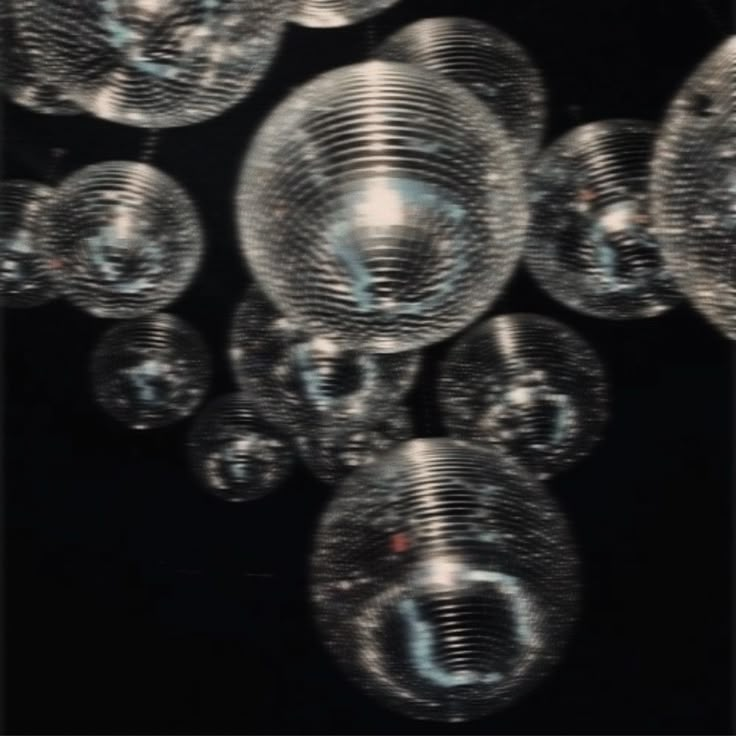 many clear glass balls hanging from the ceiling in a dark room with no one around them