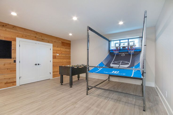 an indoor basketball court in the middle of a room with wood walls and flooring