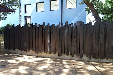 a fire hydrant in front of a blue house with a wooden fence around it