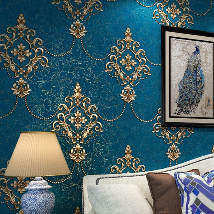 a living room with blue wallpaper and gold trimmings on the walls, along with a white couch