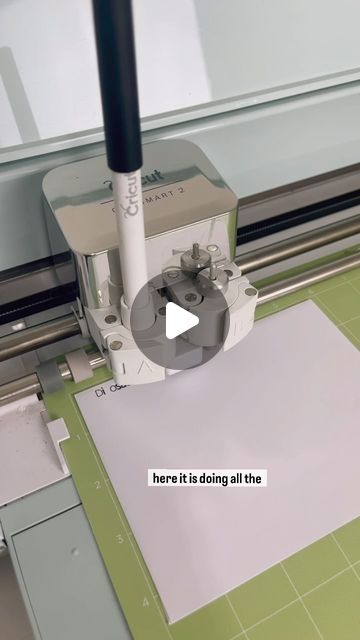 a machine that is cutting some paper on a piece of paper with the words here it is doing all the