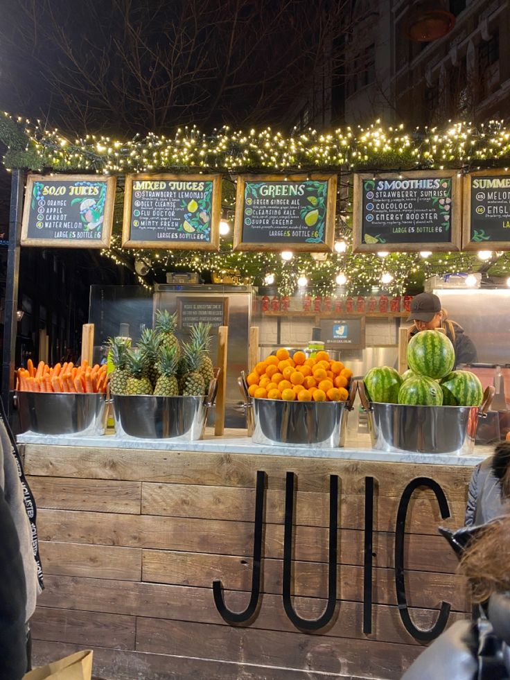 an outdoor fruit stand with lots of fresh fruits and vegetables on the counter at night