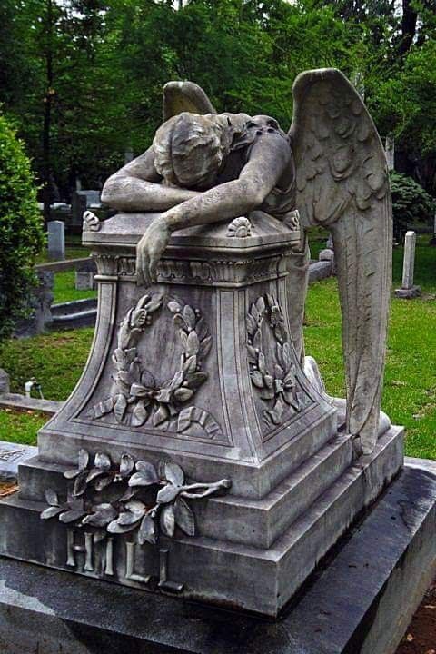 an angel statue sitting on top of a grave