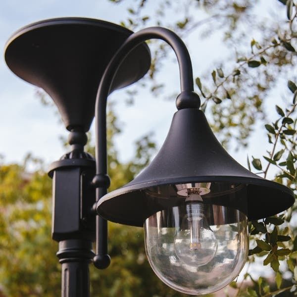 an outdoor lamp post in front of some trees