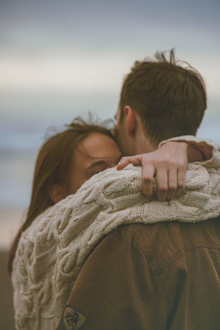 a man and woman embracing each other on the beach