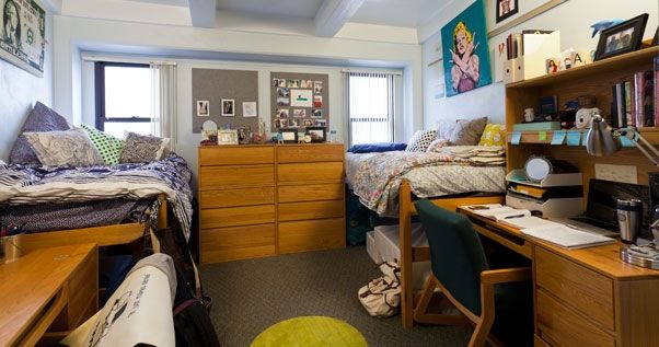 a dorm room with two beds and desks