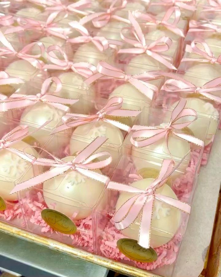 there are many chocolates wrapped in pink ribbon on the tray and tied with bows