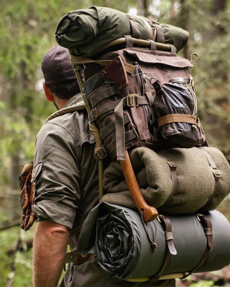 a man with a large backpack is walking through the woods and carrying something on his back