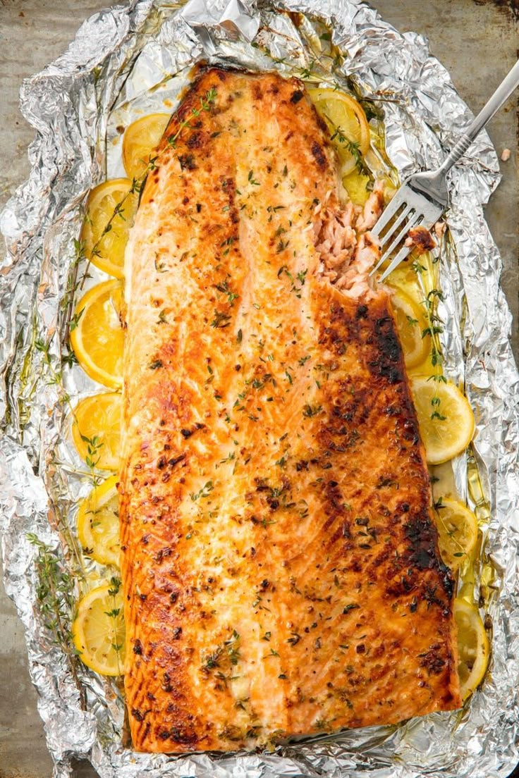 a piece of fish on foil with lemons and herbs next to it, ready to be cooked