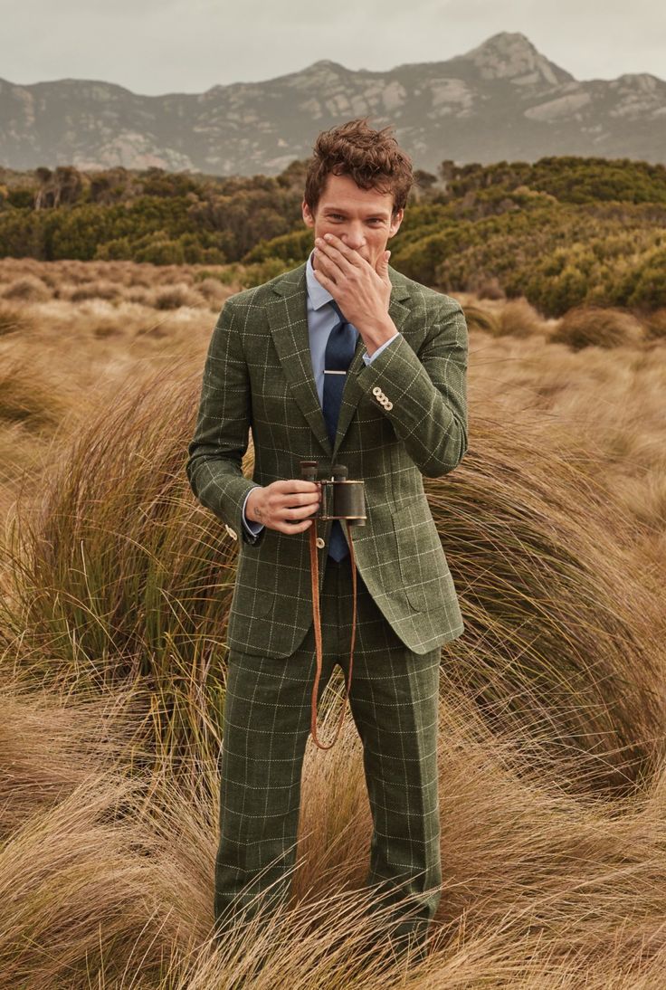 a man in a green suit and blue tie is covering his face with his hands