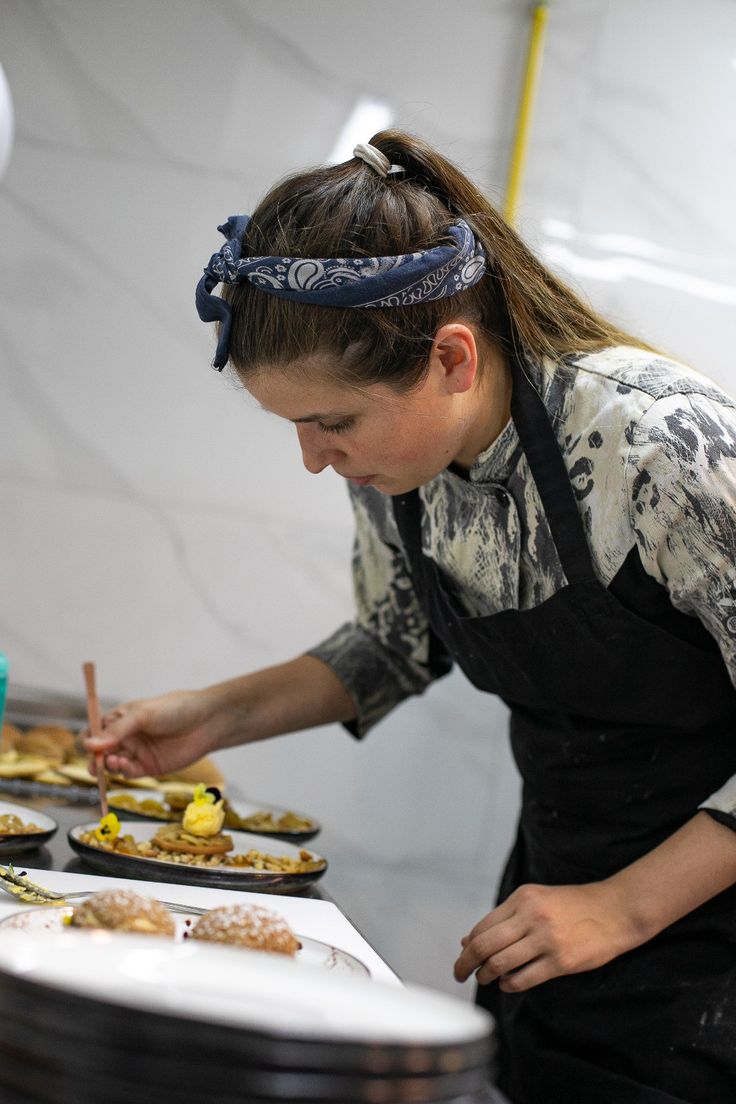 a woman in an apron preparing food on a table with plates and utensils