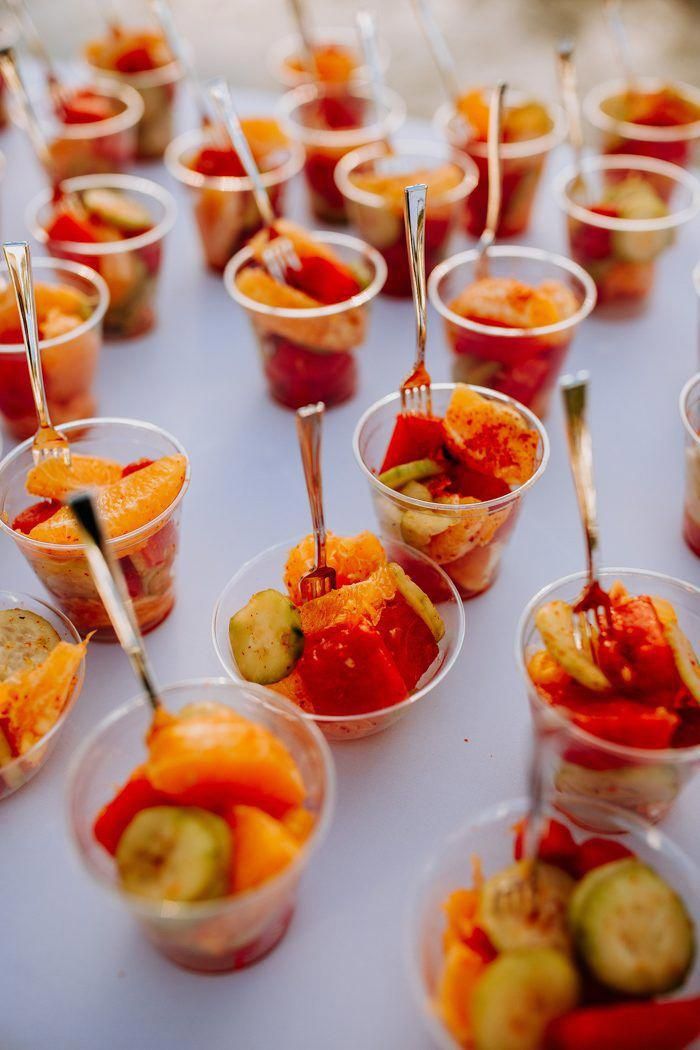 small cups filled with different types of food on top of a white cloth covered table