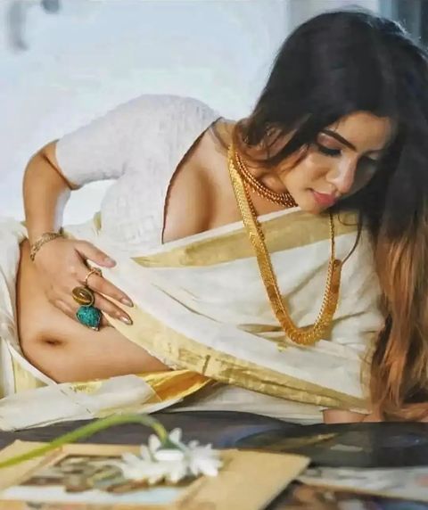 a woman laying on top of a bed wearing a white shirt and gold bracelets