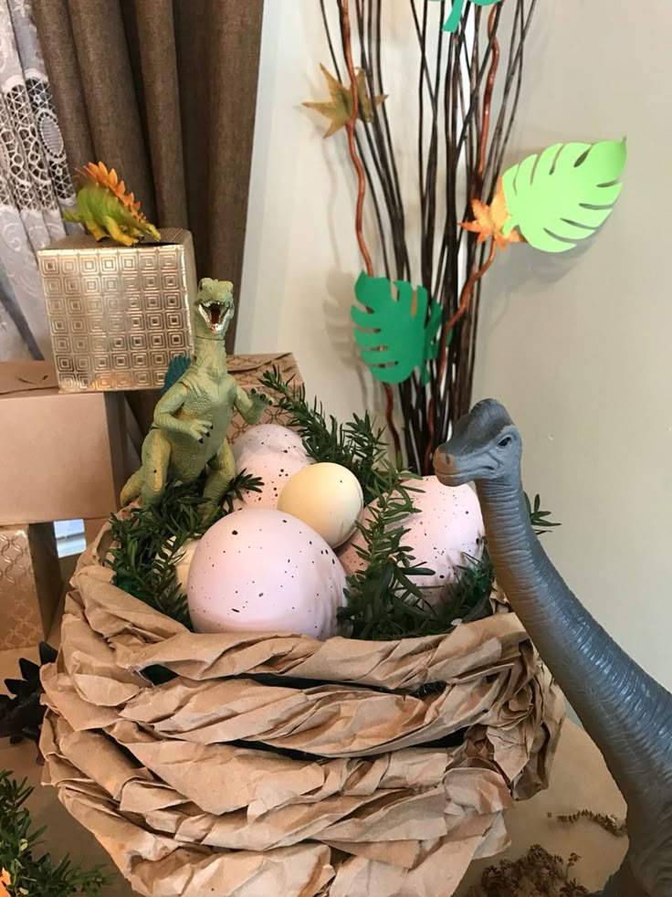 an elephant is standing next to some eggs in a basket with fake dinosaurs on it