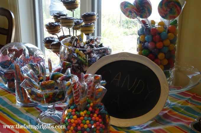 a table topped with lots of candies and cupcakes next to a chalkboard