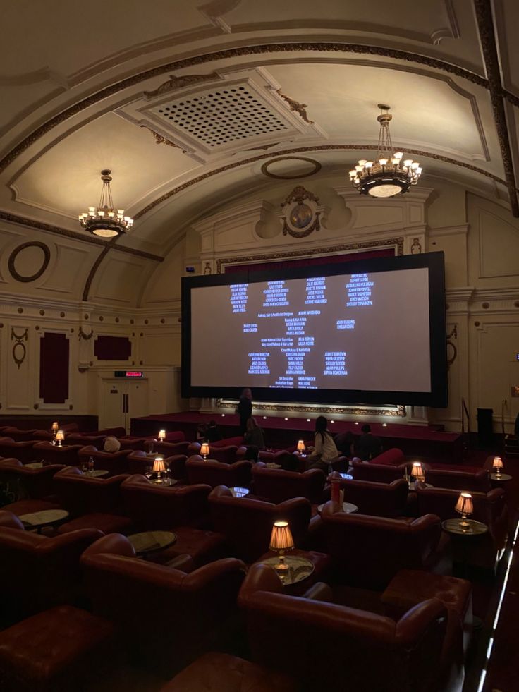 a large screen in the middle of a room filled with brown leather chairs and candles