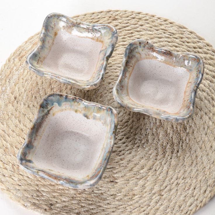 three square dishes sitting on top of a jute mat