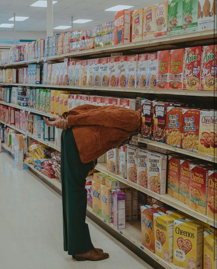 a woman standing in front of a grocery store filled with lots of cereal and milk