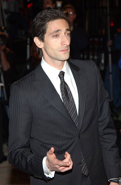 a man in a suit and tie standing on a red carpet