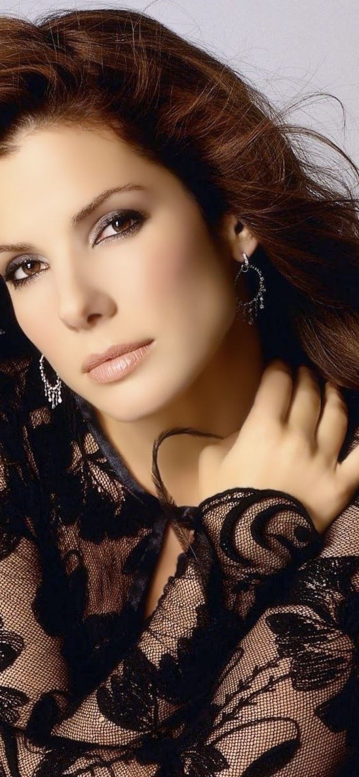 a woman with long hair and earrings on her neck posing for a photo in black lace