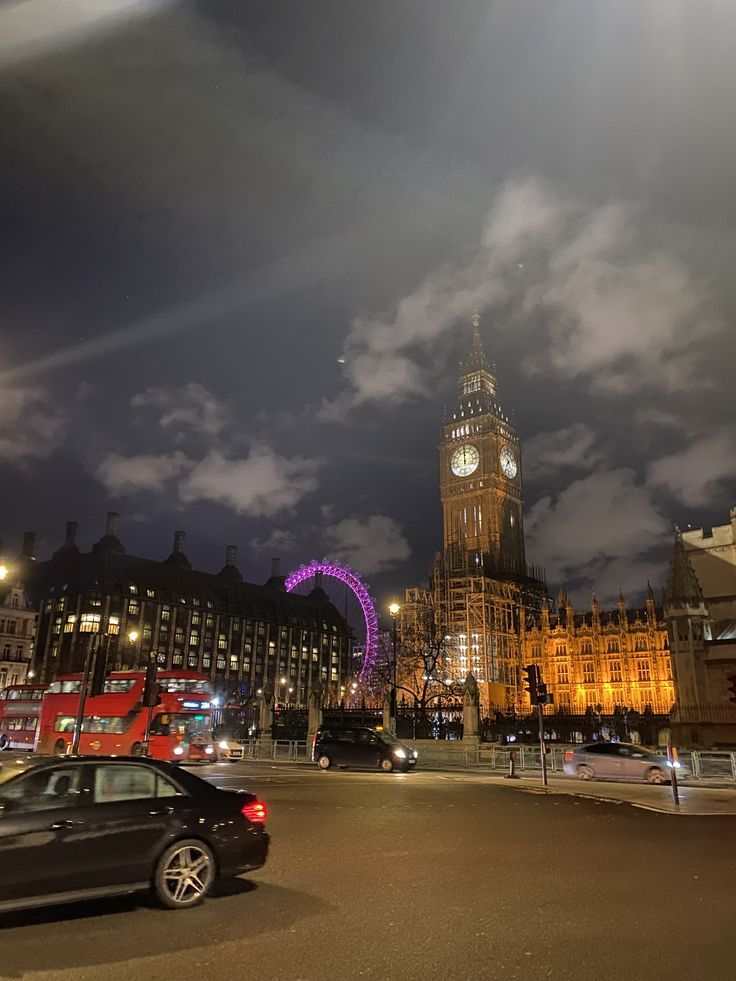 the big ben clock tower towering over the city of london at night with clouds in the sky