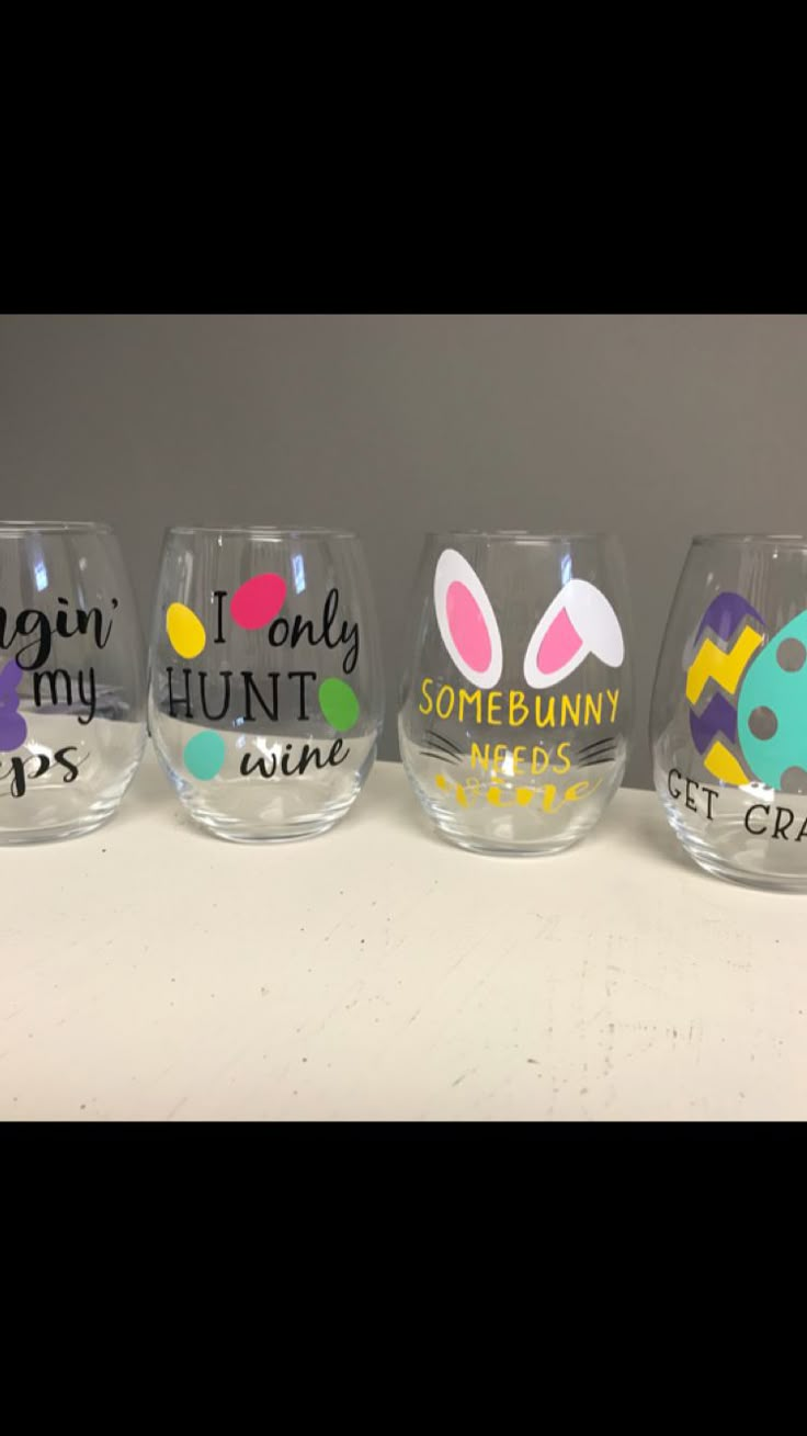 four wine glasses with different designs and words painted on the glass, one has an easter bunny