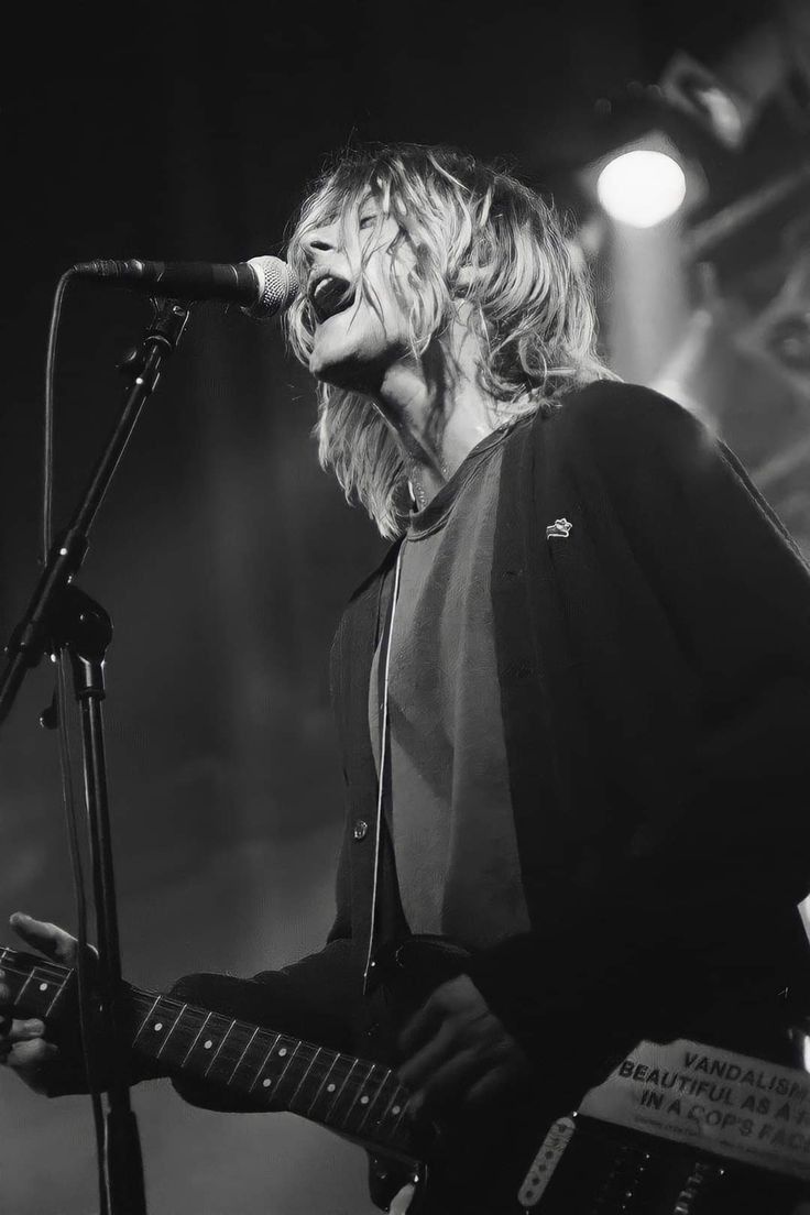 a woman singing into a microphone while holding a guitar