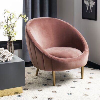 a pink chair sitting on top of a white rug next to a vase filled with flowers