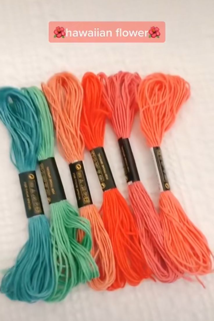 five different colors of yarn on a white surface with the words hawaiian flower written above them