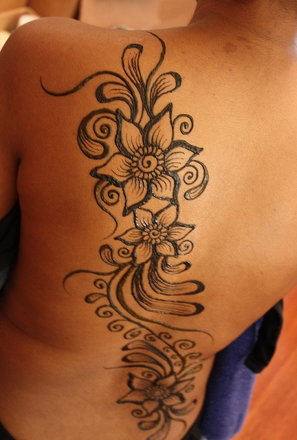 the back of a woman's shoulder with flowers on it and swirls in the middle