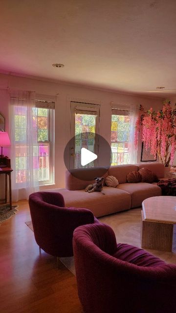 a living room filled with lots of furniture and pink flowers on the wall behind it