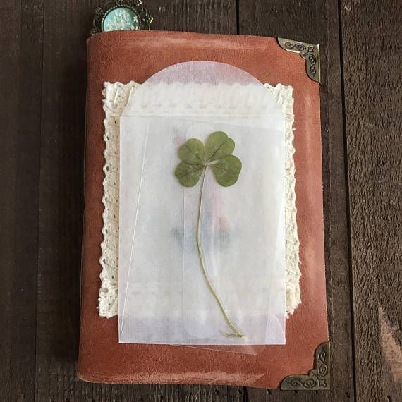 a four leaf clover is on top of a cloth covered book with lace and buttons