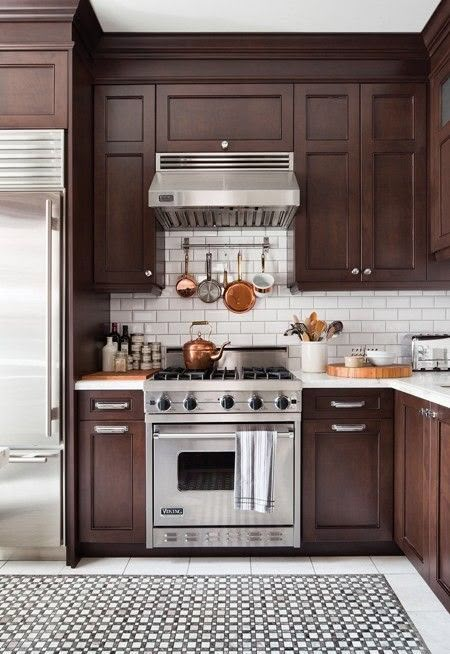 a kitchen with brown cabinets and white tile flooring, stainless steel appliances and an oven