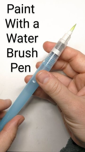 a person is holding a blue pen and writing on paper with the words paint with a water brush pen